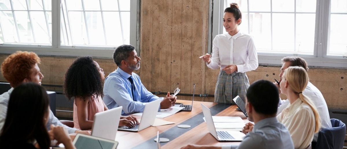 Colleagues having a discussion in a conference room with laptops and documents on the table.